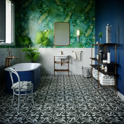 Tropical palm wallpapered bathroom with white tiles, blue tub, patterned floor tiles, and shelves with towels and toiletries.