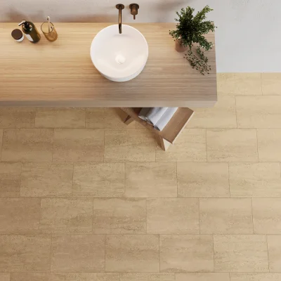 Overhead view of a light wooden bathroom vanity with a round white vessel sink and dark tap; a potted plant on the right, bottles on the left, and towels beneath.
