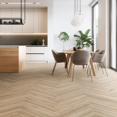 Bright open-plan kitchen and dining area with a wooden island, beige cabinets, and a dining table with grey chairs; herringbone floor, plants.