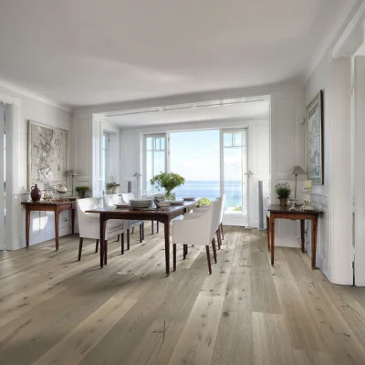 Bright dining room with a wooden table and white chairs, side tables with lamps, and large windows overlooking a sea view.
