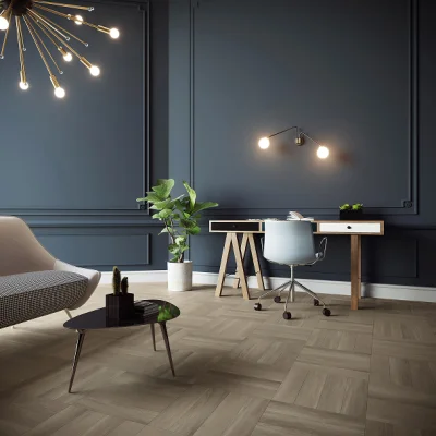 Modern home office with dark blue paneled walls, parquet floor, a wooden desk with a white swivel chair, a potted plant, and a starburst ceiling light.