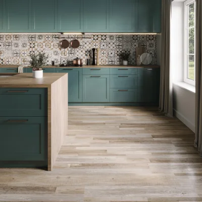 Teal kitchen with patterned tile backsplash, wooden island, copper cookware, a potted plant and a large window with curtains letting in soft light.