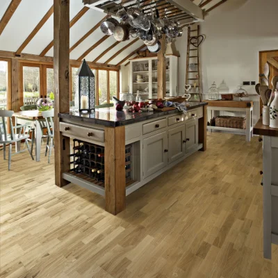 Rustic kitchen featuring a central wooden island, hanging pots, a wine rack, exposed beams, and light wooden flooring beneath large windows.