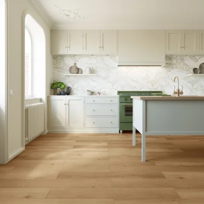 Bright kitchen with white cabinets, marble backsplash, light hardwood floor; green range, pale blue island, brass faucet, arched window, plant.