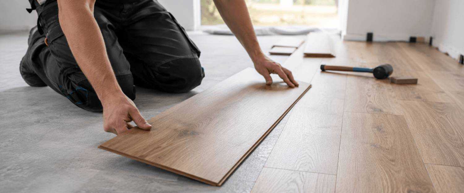 Professional fitter installing oak laminate flooring using a click-lock system in a modern home